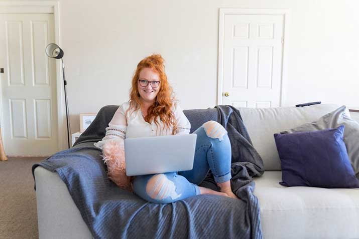 Open Universities Australia student Kimberley, set up to study on her sofa with a laptop computer.