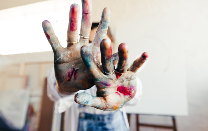 An artist's hands covered in paint