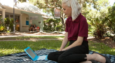 Open Universities Australia student Josephine, set up to study on a picnic blanket with a laptop computer outdoors.